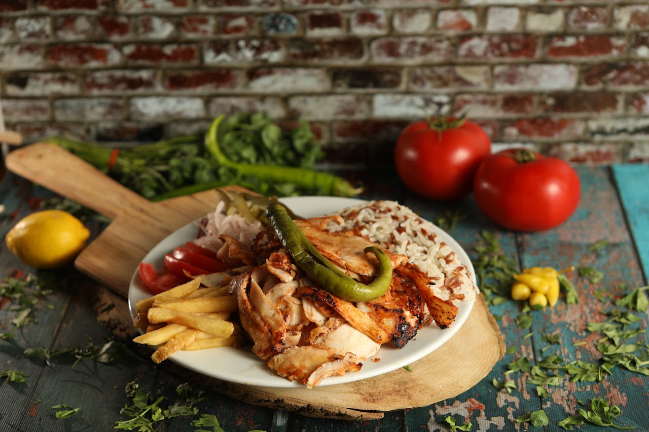 A mouthwatering plate of Turkish doner kebab with fries, rice, and vegetables in a rustic setting.
